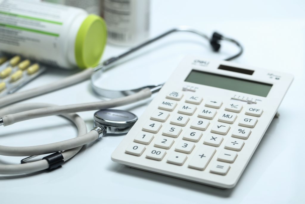 calculator stethoscope medicine bottles white background